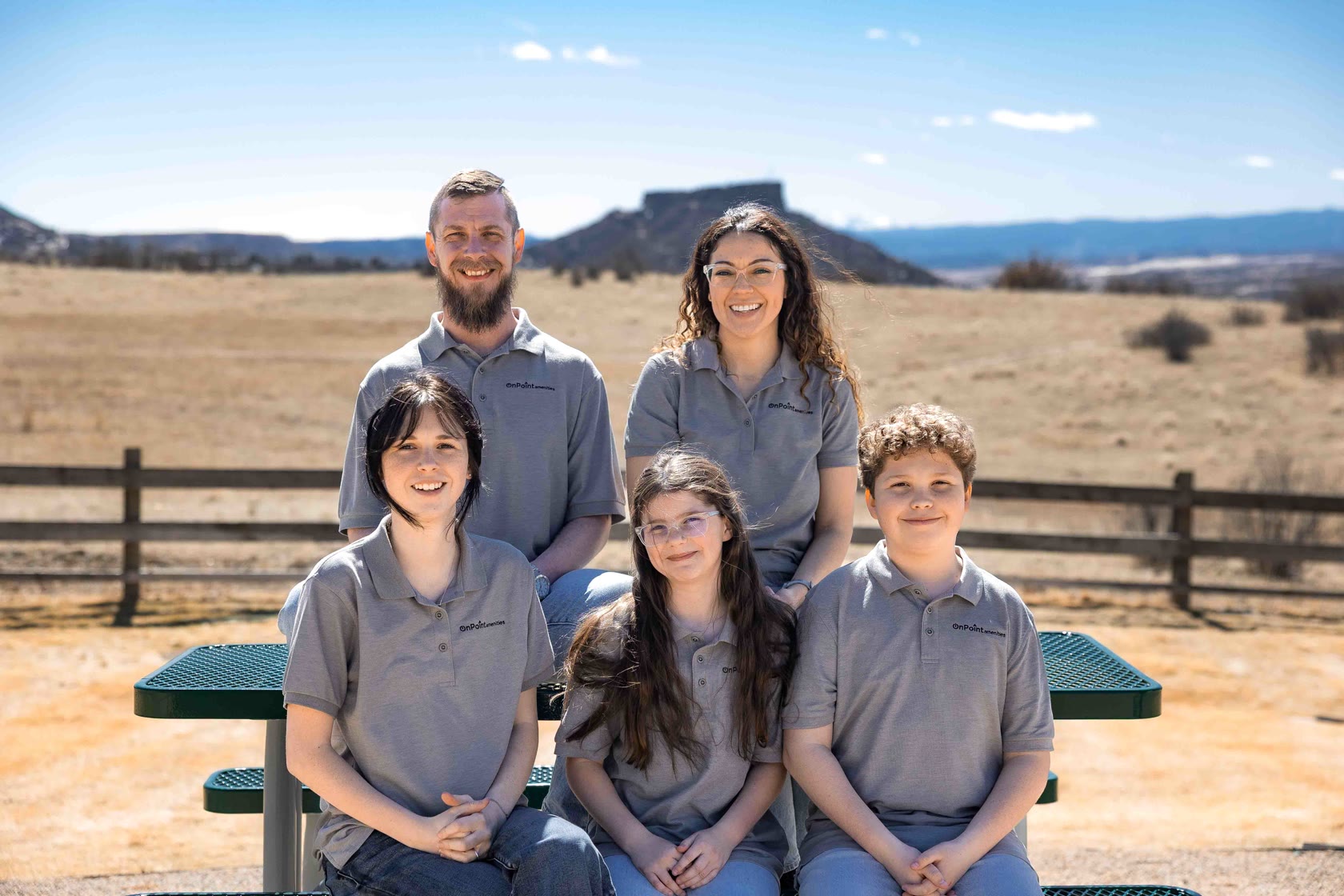 The Krakow family in On Point Amenities polos, with the Castle Rock butte behind them