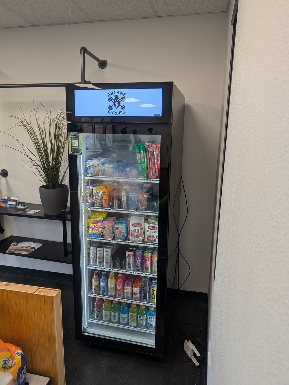 On Point smart cooler at Arcane Barbell carrying the gym's own logo on its screen, stocked with protein and recovery products